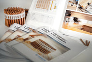 Woodworking magazines on a table with a basket of pencils and a workshop in the background